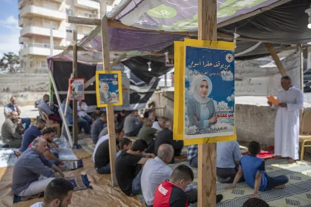 Palestinians attend Friday prayers under posters with picture and name of Mai Afaneh, who was shot dead by Israeli forces in the West Bank last June and held her body after, and reads “who can stop the dark grudge”, at a sit-in tent for families of Palestinians killed in conflict and Israel is holding their bodies, in the village of Abu Dis, South of Ramallah, Friday, September 24, 2021. (Photo by Nasser Nasser/AP Photo)