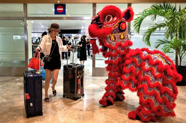 A dragon dance performer greets a traveler from China at the Ninoy Aquino International Airport, in Pasay City, Metro Manila, Philippines on January 24, 2023. (Photo by Lisa Marie David/Reuters)