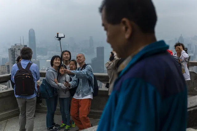 Tourists take photographs from a lookout on Victoria Peak in Hong Kong, China, 01 April 2019. Hong Kong is experiencing the northeast monsoon which is bringing cloudy weather with rain patches and fresh easterly winds. (Photo by Jerome Favre/EPA/EFE)