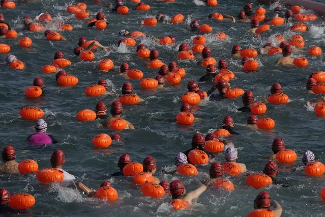 Competitors swim during a harbor race at the Victoria Harbor in Hong Kong, Sunday, December 12, 2021. Hundreds of people took part in traditional swim across iconic Victoria Harbor after two years of suspension. (Photo by Kin Cheung/AP Photo)