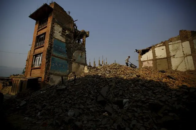 A man pushes cart filled with bricks, as he removes debris from collapsed houses, a month after the April 25 earthquake in Kathmandu, Nepal May 25, 2015. (Photo by Navesh Chitrakar/Reuters)