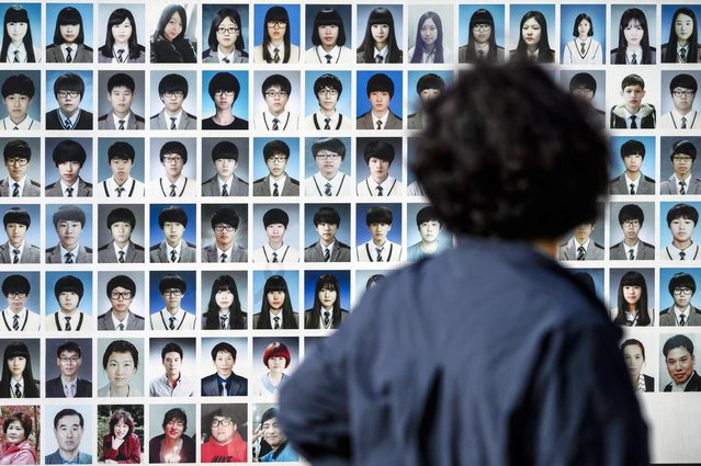 A woman looks at photos of victims after a remembrance ceremony in front of the salvaged Sewol ferry at a port in Mokpo, South Jeolla Province, on April 16, 2024, as South Korea marked the 10th anniversary of the country's worst-ever maritime disaster, when hundreds of schoolchildren died after the overloaded Sewol ferry capsized and sank. (Photo by Anthony Wallace/AFP Photo)