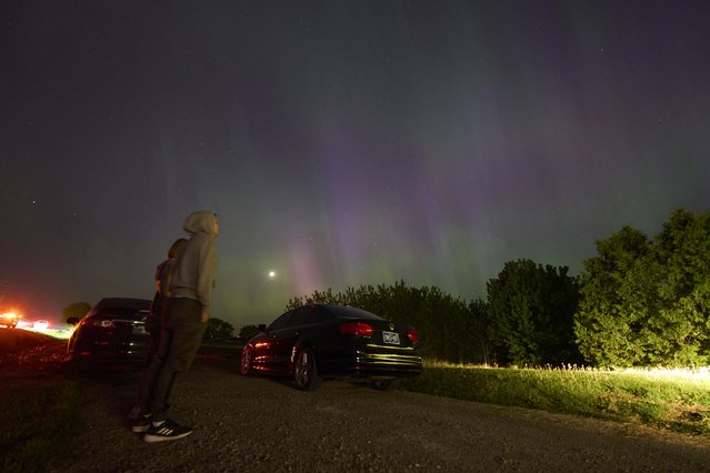 People stop along a country road near London, Ontario to watch the Northern lights or aurora borealis during a geomagnetic storm on May 10, 2024. The most powerful solar storm in more than two decades struck Earth on May10, 2024, triggering spectacular celestial light shows in skies from Tasmania to Britain – and threatening possible disruptions to satellites and power grids as it persists into the weekend. Auroras are often observed in Canada's northern regions, but rarely in southern Ontario. (Photo by Geoff Robins/AFP Photo)