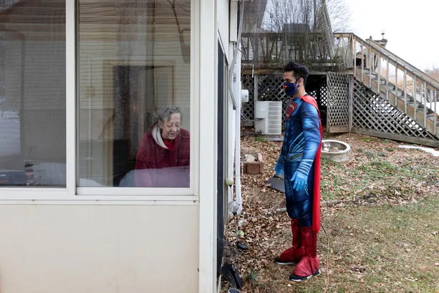 Dr. Mayank Amin opens the door of Nancy Higgins's basement to surprise her with the Moderna coronavirus disease (COVID-19) vaccine in Trappe, Pennsylvania, U.S., February 27, 2021. On a gray Saturday morning in late February, Amin slipped into a Superman costume, the remnant of Halloweens past that he now sometimes wears for vaccinations, and drove through the frozen suburbs to deliver two COVID-19 vaccines to home-bound patients. (Photo by Hannah Beier/Reuters)