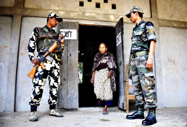 Indian security personnel look on as a voter leaves a polling station after casting her ballot in Kahnmun, some 190 kms from Aizwal, the capital of the northeastern Indian state of Mizoram on April 11, 2014. Indians began voting April 7 in the world's biggest election, which is set to sweep the Hindu nationalist opposition to power at a time of low growth, anger over corruption and warnings about religious unrest. Elections are being held in nine phases from April 7 until May 12. (Photo by Arindam Dey/AFP Photo)