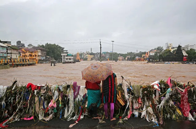 Women watch submerged temples and houses from a bridge covered with garbage by the waters of overflowing river Godavari after heavy rainfall in Nashik, India, August 5, 2019. (Photo by Francis Mascarenhas/Reuters)