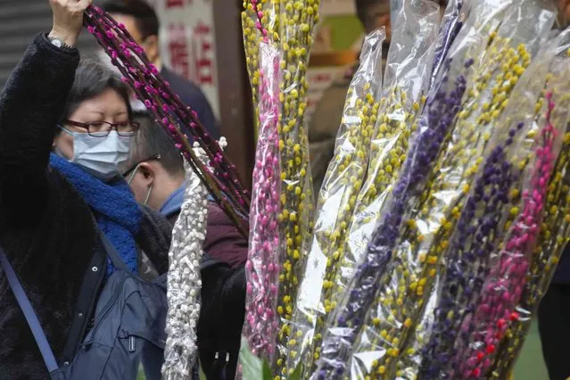 A woman purchases flowers at a market to celebrate the Lunar New Year in Hong Kong, Monday, January 31, 2022. The Chinese Lunar New Year falls on Feb. 1. (Photo by Vincent Yu/AP Photo)