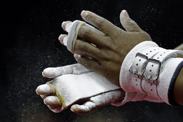 Simone Biles chalks her hands before working on the uneven bars during practice for the U.S. Gymnastics Championships Wednesday, August 7, 2019, in Kansas City, Mo. (Photo by Charlie Riedel/AP Photo)