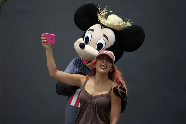 A woman poses for a photo with a street performer in a Mickey Mouse costume in Old San Juan, Puerto Rico, Wednesday, July 1, 2015, the day a 11.5% sales tax goes into effect, the highest of any U.S. state. The island's administration has been pushing for Congress to let the government and public agencies seek bankruptcy protection, while the White House has said no one is contemplating a federal bailout of Puerto Rico. (Photo by Ricardo Arduengo/AP Photo)