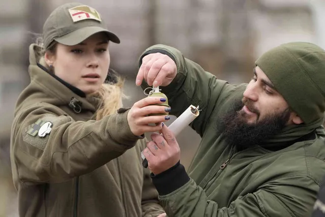 An instructor shows a young woman how to use a grenade during a training with members of the Georgian Legion, a paramilitary unit formed mainly by ethnic Georgian volunteers to fight against the Russian aggression in Ukraine in 2014, in Kyiv, Ukraine, Saturday, February 19, 2022. Separatist leaders in eastern Ukraine have ordered a full military mobilization amid growing fears in the West that Russia is planning to invade the neighboring country. The announcement on Saturday came amid a spike in violence along the line of contact between Ukrainian forces and the pro-Russia rebels in recent days. (Photo by Efrem Lukatsky/AP Photo)