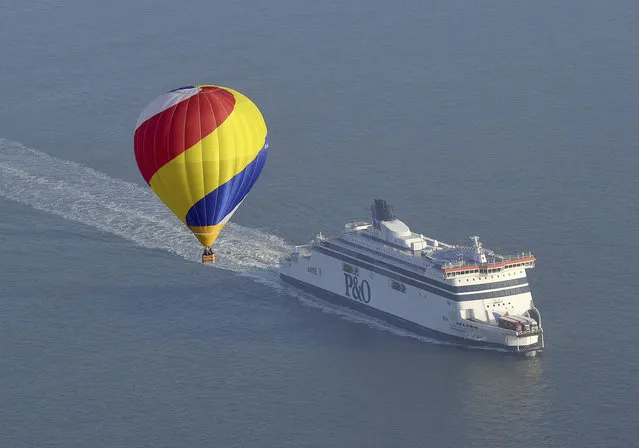 One of the 100 balloons taking part in a World Record attempt for a mass hot air balloon crossing of the English Channel, flies over a cross channel ferry near the Port of Dover in Kent, England, Friday April 7, 2017. (Photo by Victoria Jones/PA Wire via AP Photo)