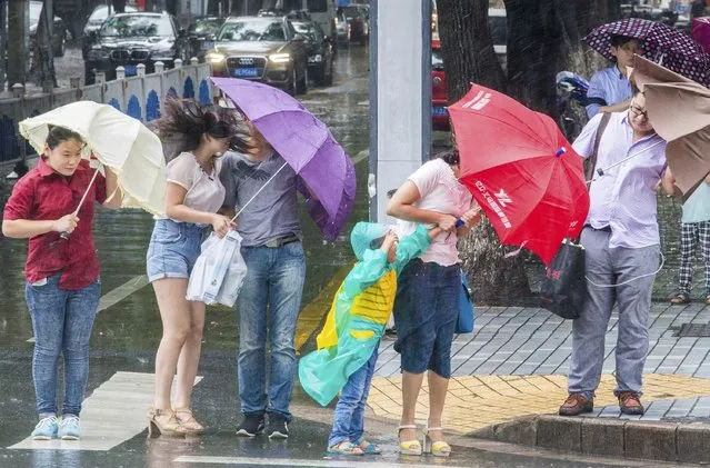Pedestrians hold their umbrellas on a street against strong wind under the influence of Typhoon Chan-hom, in Kunshan, Jiangsu province, China, July 11, 2015. (Photo by Reuters/Stringer)