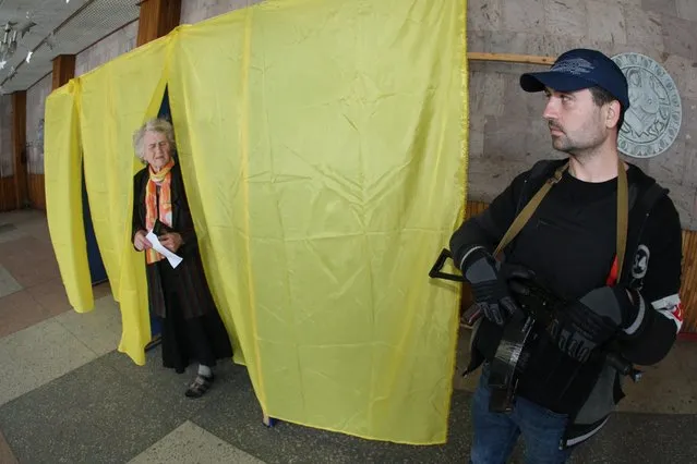 An armed pro-Russian activists stands guard near a polling booth during the referendum called by pro-Russian rebels to split from the rest of Ukraine, on May 11, 2014 in Donetsk. (Photo by Alexander Khudoteply/AFP Photo)