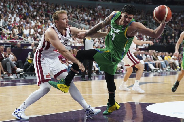 Brazil's Gui Santos, right, struggles for the ball with Latvia's Arturs Strautins during the men's Basketball Olympic qualifying final match between Latvia and Brazil, in Riga, Latvia, Sunday, July 7, 2024. (Photo by Roman Koksarov/AP Photo)