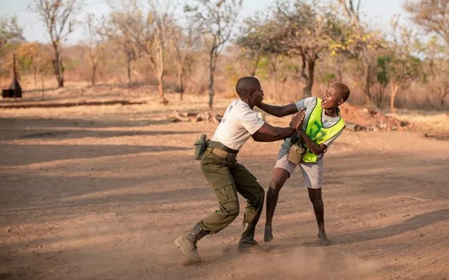 A new recruit, coming from disadvantage and abusive background, and going through a selection process to join the Akashinga Ranger training programme, wrestles with an instructor as part of an anti-bullying exercise, during their selection process in Phundundu, Zimbabwe on September 17, 2019. The programme was started in Phundundu Wildlife Area in Zimbabwe's Lower Zambezi ecosystem. It builds an alternative approach to the militarised paradigm of 'fortress conservation' which defends colonial boundaries between nature and humans. While still trained to deal with any situation they may face, the team has a community-driven interpersonal focus, working with rather than against the local population for the long-term benefits of their own communities and nature. (Photo by Gianluigi Guercia/AFP Photo)