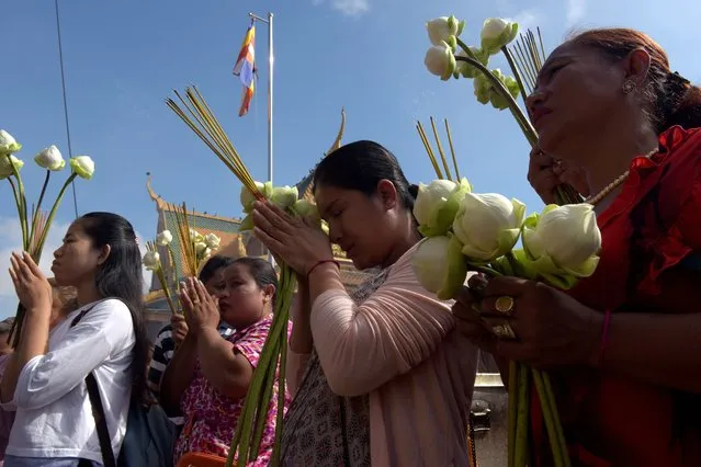 Cambodian women pray in front of a shrine out side the Royal Palace in Phnom Penh on May 10, 2017. Cambodian celebrate 2,561 years of Buddha, called “Visak Bochea”, that is the date of Buddha's birth, enlightenment and death on the day of the full moon. (Photo by Tang Chhin Sothy/AFP Photo)