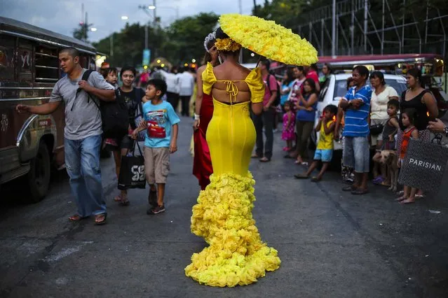 Joel Mondano walks in a dress beside pedestrians and commuters as she participates in a transgender parade called “Grand Trans-Santacruzan” on International Day Against Homophobia and Transphobia in suburban Quezon city, north of Manila, Philippines, on May 18, 2014. The Santacruzan is a popular religious festival held in many towns and cities throughout this largely Roman Catholic country. (Photo by Aaron Favila/Associated Press)