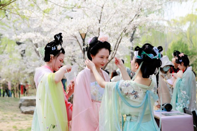 Girls in Han costumes pose for a photo with blooming cherry blossoms at Yuyuantan Park during Qingming Festival holiday on April 4, 2022 in Beijing, China. Qingming Festival, also known as Tomb Sweeping Day, falls on April 5 this year. (Photo by Zhao Naiming/VCG via Getty Images)