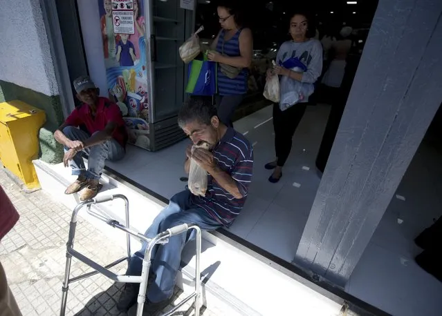 In this March 20, 2017 photo, a man eats bread after buying it at a private bakery in Caracas, Venezuela. In an attempt to control the production of subsidized bread, the government is carrying spot checks targeting some 700 bakeries, and authorities have even announced the arrest of two people for making illegal brownies. (Photo by Fernando Llano/AP Photo)