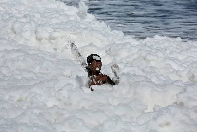 A boy plays with foam formed from pollution at the Marina beach in Chennai, India, November 29. 2019. (Photo by P. Ravikumar/Reuters)