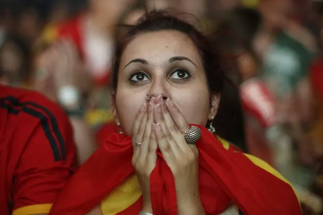 A Spanish soccer fan covers her face as she watches on a giant display a World Cup soccer match between Spain and Chile, in Madrid, Spain, Wednesday, June 18, 2014. (Photo by Andres Kudacki/AP Photo)