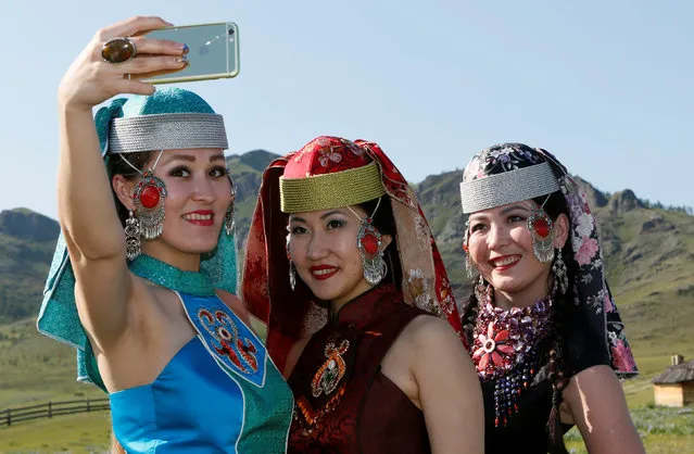 Models of the “Altyr” fashion theatre, dressed in Khakas national costumes, take a selfie during a break in a photo session, as a part of the rehearsal for the Tun-Pairam traditional holiday (The Holiday of the First Milk) celebration at a museum preserve outside Kazanovka village near Abakan in the Republic of Khakassia, Russia, May 28, 2016. (Photo by Ilya Naymushin/Reuters)