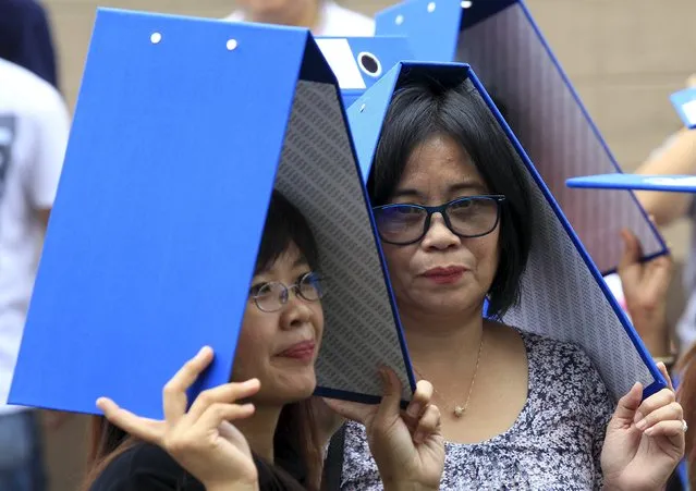Government employees cover their heads with folders as they participate in an earthquake drill at the city hall of Pasay city, metro Manila July 29, 2015. The earthquake drill is part of the local government's preparation if ever a major earthquake strikes the country, a representative from the city hall said. (Photo by Romeo Ranoco/Reuters)