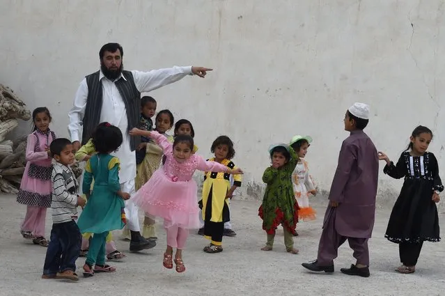 In this photograph taken on March 23, 2016, Pakistani father Sardar Haji Jan Mohammad Khilji plays with some of his children at his residence in Quetta. A Pakistani father of 35 is now searching for a fourth wife as he romps towards his goal of 100 children, a dubious ambition in the conservative Muslim country where polygamy is rare but still practiced. (Photo by Banaras Khan/AFP Photo)