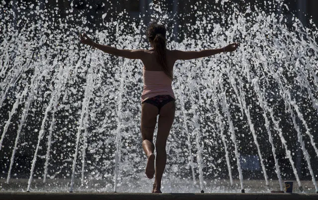 A woman doing yoga at a fountain, in downtown Stuttgart, Germany, Thursday, June 22, 2017. Weather forecasts predict hot summer weather as well as thunderstorms for some parts of Germany. (Photo by Marijan Murat/DPA via AP Photo)