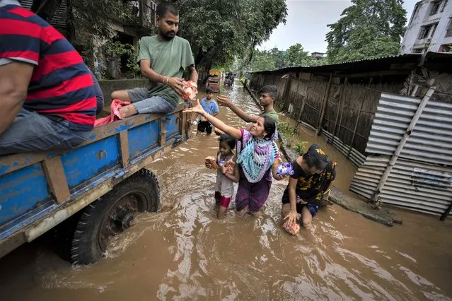 Municipal workers distribute food and water to flood affected people after continuous rainfall in Gauhati, India, Wednesday, June 15, 2022. (Photo by Anupam Nath/AP Photo)