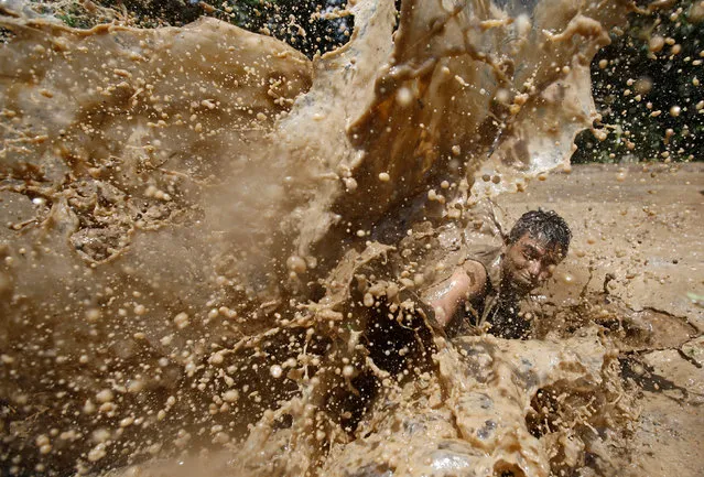A student of Himalayan Agriculture College plays in the mud while celebrating Asar Pandra festival in Lalitpur, Nepal, June 29, 2016. (Photo by Navesh Chitrakar/Reuters)