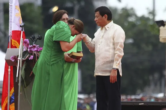 Philippine Vice President-elect Sara Duterte, left, places the hands of her father, outgoing Philippine President Rodrigo Duterte, on her forehead as a sign of respect during her oath taking rites as vice president in her hometown in Davao city, southern Philippines on Sunday June 19, 2022. Duterte clinched a landslide electoral victory despite her father's human rights record that saw thousands of drug suspects gunned down. (Photo by Manman Dejeto/AP Photo)
