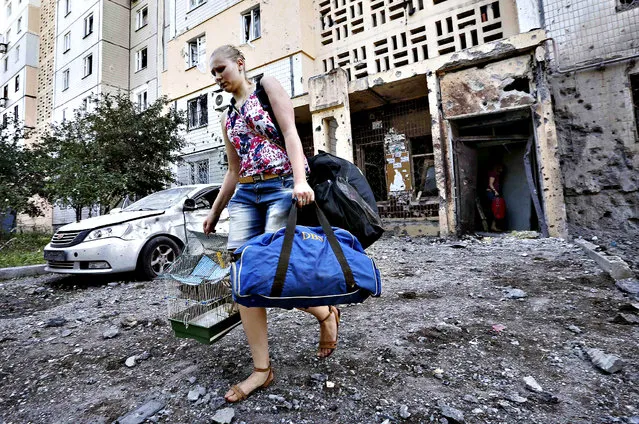 A woman walks out of a damaged multi-storey block of flats carrying her belongings following what locals say was recent shelling by Ukrainian forces in central Donetsk...A woman walks out of a damaged multi-storey block of flats carrying her belongings following what locals say was recent shelling by Ukrainian forces in central Donetsk, July 29, 2014. (Photo by Sergei Karpukhin/Reuters)