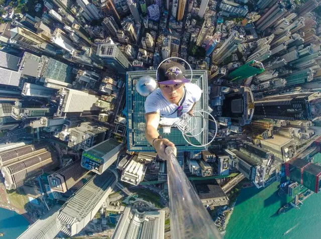 Roof-topping enthusiast Daniel Lau takes a selfie with high-rise buildings down below as he stands on the top of a skyscraper in Hong Kong, China on August 15, 2017. Welcome to “roof-topping”, where daredevils take pictures of themselves standing on the tops of tall buildings, or in some cases even dangling from them, without any safety equipment. A craze that began in Russia has now taken hold in Hong Kong, one of the world's most vertical cities, with dramatic results. “I'm an explorer”, said Daniel Lau, one of the three who climbed to the top of The Center. A student, he said roof-topping was “a getaway from my structured life”. “Before doing this, I lived like an ordinary person, having a boring life”, he said. “I wanted to do something special, something memorable. I want to let people see Hong Kong, the place they are living, from a new perspective”. Mr Lau said he had been inspired by Russian climbers and that he was unafraid of the vertiginous heights he scales. (Photo by ImagineChina/Rex Features/Shutterstock)