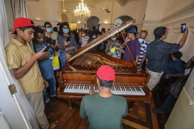 People sing songs inside the prime minister's official residence in Colombo, Sri Lanka, 12 July 2022, three days after official residences were stormed. Sri Lankan president and prime minister agreed to resign after a party leaders' meeting during a day of massive anti-government protests. Thousands of protesters on 09 July broke through police barricades and stormed the President's palace, President's secretariat, and the prime minister's official residences. Protest have been rocking the country over months, calling for the resignation of the president and prime minister over the alleged failure to address the worst economic crisis in decades. (Photo by Chamila Karunarathne/EPA/EFE)