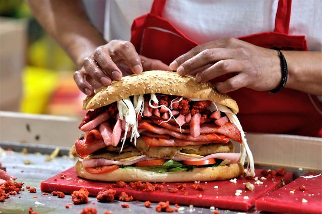 Preparation of a Cuban cake (a Mexican sandwich that is made with bread, generally a telera, bolillo or baguette, which is split in half and filled with different ingredients such as milanesa, sausages, cheese, avocado, onion, tomato, bacon, chili, chorizo, pineapple, among others), during the International Cake Fair on the esplanade of the Venustiano Carranza mayor's office in Mexico City on August 2, 2023. (Photo by Gerardo Vieyra/NurPhoto/Rex Features/Shutterstock)