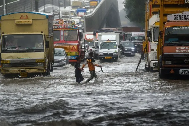 Vehicles drive through flooded street during rain showers in Mumbai on July 5, 2022. (Photo by Punit Paranjpe/AFP Photo)