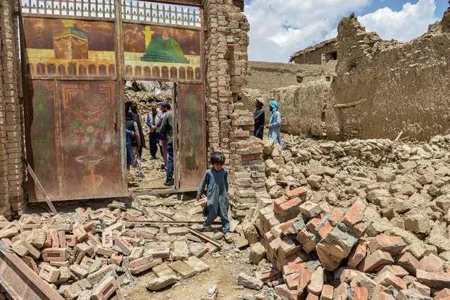 A child walks out from inside a gate of a house damaged by an earthquake in Bermal district, Paktika province, on June 23, 2022. Desperate rescuers battled against the clock and heavy rain on June 23 to reach cut-off areas in eastern Afghanistan after a powerful earthquake killed at least 1,000 people and left thousands more homeless. (Photo by Ahmad Sahel Arman/AFP Photo)