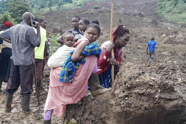 Rescue workers and people search for bodies after a landslide following heavy rains that buried 40 homes in the mountainous district of Bulambuli, eastern Uganda, Thursday, November 28. 2024. (Photo by Jean Watala/AP Photo)