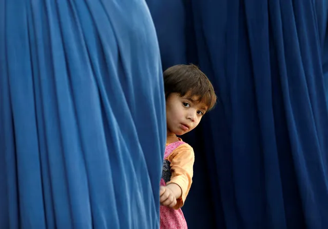 An Afghan girl holds her mother's burqa as she waits to receive aid from the Afghanistan Chamber of Commerce and Industries (ACCI) during the month of Ramadan in Kabul, Afghanistan June 23, 2016. (Photo by Mohammad Ismail/Reuters)