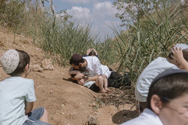 Israelis take cover as a siren sounds a warning of incoming rockets fired from the Gaza Strip in Rehovot, Israel, Friday, October 13, 2023. (Photo by Dor Kedmi/AP Photo)