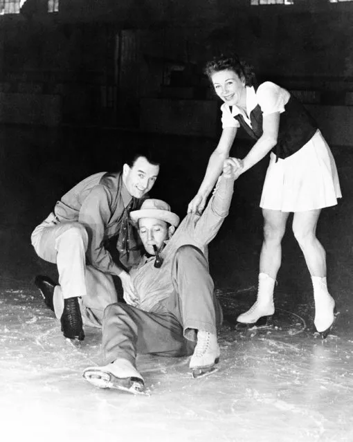 Bing Crosby shows how not to display the finer points of ice skating at the Broadmoor Ice Palace at Colorado Springs on June 17, 1943.  Even Bruce Mapes and Evelyn Chandler, professional skaters, can't keep the crooner on his feet. (Photo by AP Photo)