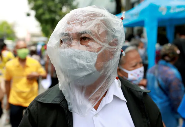 A man affected by the government's measures against the spread of the coronavirus disease (COVID-19) wears a protective face covering as he lines up for filing forms to request three months of monthly financial aid from the government in front of the Finance Ministry in Bangkok, Thailand, May 1, 2020. (Photo by Soe Zeya Tun/Reuters)
