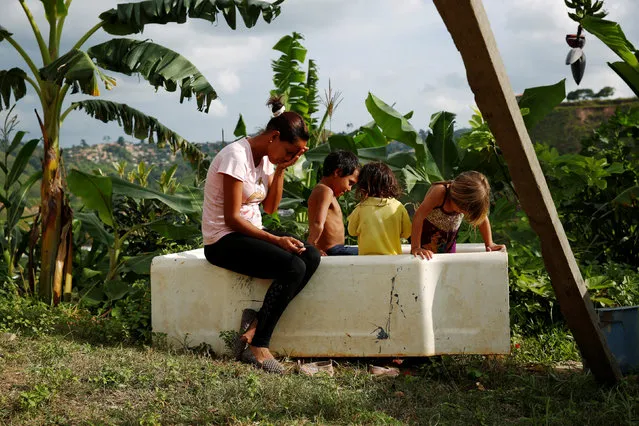 Lisibeht Martinez (L), 30, who was sterilized one year ago, sits next to her children while they play in a bathtub in the backyard of their house in Los Teques, Venezuela July 19, 2016. (Photo by Carlos Garcia Rawlins/Reuters)