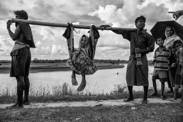 A Rohingya refugee woman is carried by relatives near the border on the Bangladesh side of the Naf River after fleeing Myanmar, on October 2, 2017 in Cox's Bazar, Bangladesh. (Photo by Kevin Frayer/Getty Images)