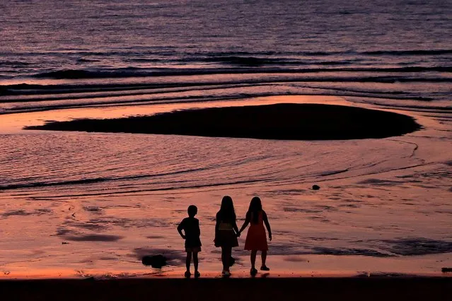 Children enjoy the sea view during sunset hours in New Taipei city, Taiwan on August 4, 2022. (Photo by Ann Wang/Reuters)