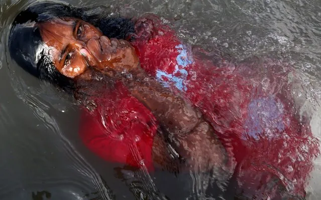 A child emerges from the water as she cools off in a water basin to beat the scorching heat on a summer day in Bhopal, India, 29 May 2020. The temperature of the city has reached 45 degrees Celsius, according to reports. (Photo by Sanjeev Gupta/EPA/EFE)
