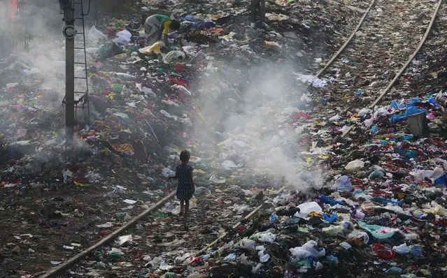 A girl walks on a railway track past piles of  dumped garbage in Mumbai, India, Thursday, October 2, 2014.Millions of schoolchildren, officials and ordinary people picked up brooms and dustpans Thursday to join a countrywide campaign to clean parks, public buildings and streets. (Photo by Rafiq Maqbool/AP Photo)
