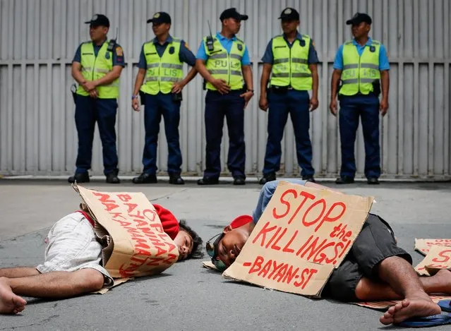Filipino demonstrators (foreground) mimic an extrajudicial killing crime scene as police officers stand guard during a protest in front of the Philippine National Police (PNP) headquarters in Camp Crame, Quezon City, northeast of Manila, Philippines, 26 August 2016. According to police data which was submitted to a Senate investigation on 23 August by PNP Director General Ronald Dela Rosa, at least 756 people were slain during anti-drug police operations and 1,160 more deaths were committed by still unknown assailants based on a tally from 01 July to 23 August, putting the overall toll of lives at 1,916 or an average of 36 deaths per day, killed in a violent campaign against drugs in the Philippines since President Rodrigo Duterte took office, the country's national police chief said. (Photo by Mark R. Cristino/EPA)