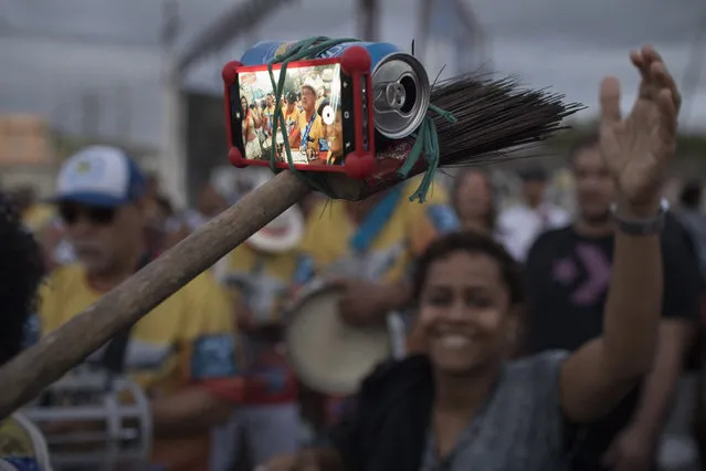 A samba band member turns a broom, beer can and rubber band into a selfie stick at the Oswaldo Cruz neighborhood, marking Samba Day, in Rio de Janeiro, Brazil, Saturday, December 2, 2017. The Samba Train is made up of several normal commuter metro trains filled with Samba musicians to transport revelers to the Oswaldo Cruz neighborhood for music shows, all in commemoration of National Samba Day. (Photo by Leo Correa/AP Photo)